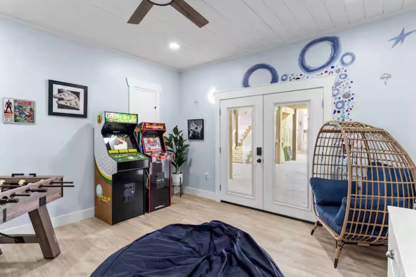 Arcade room from the other side: hanging egg chair, French doors, and game consoles