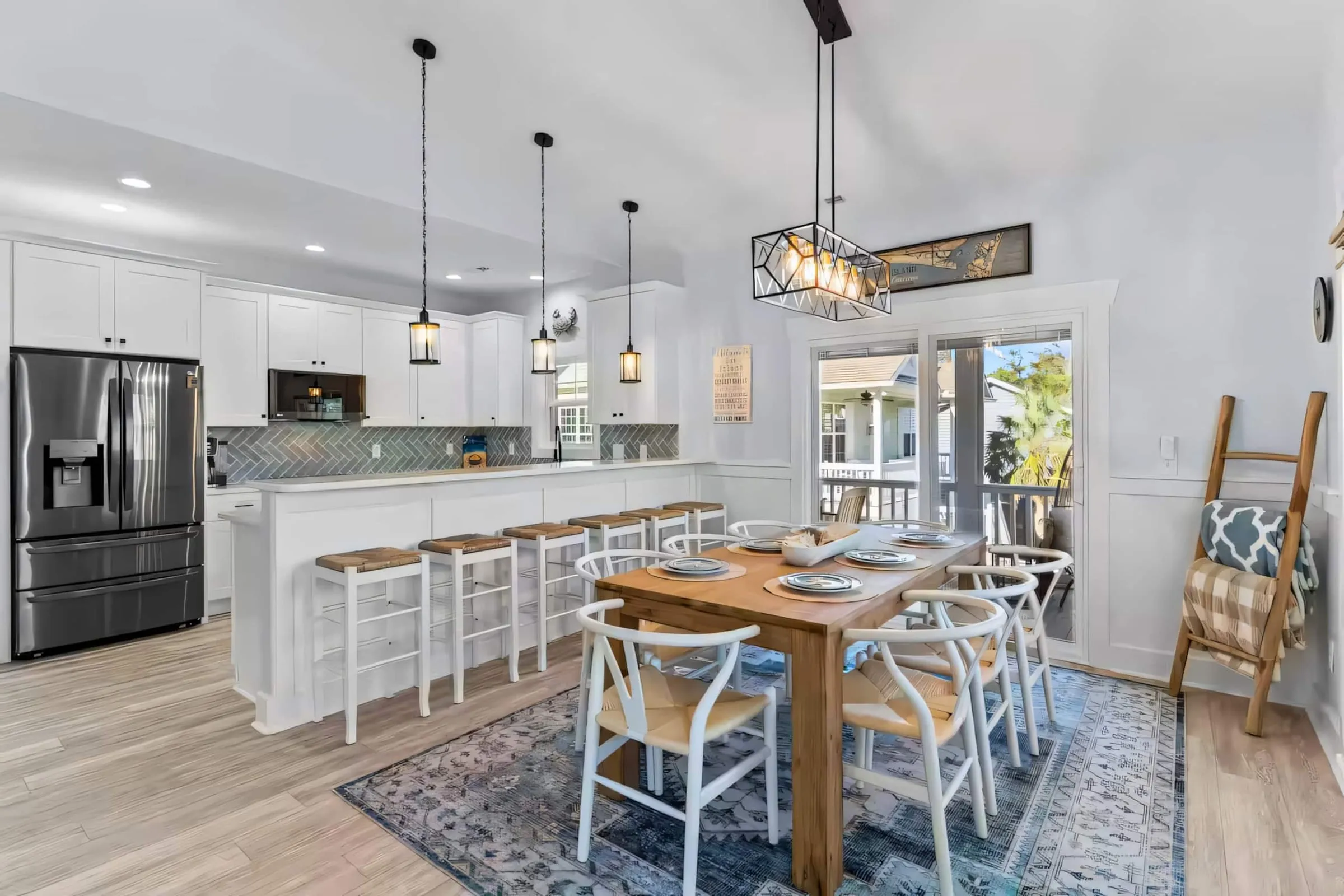Open kitchen and dining area with a long island, bar stools, pendant lights, and a farmhouse table